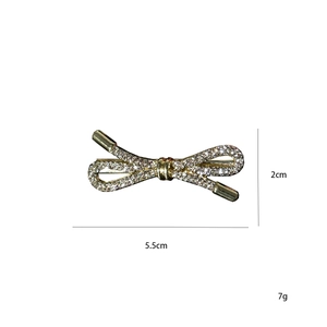 Detailed view of a golden rhinestone bow brooch with 5.5cm x 2cm size specifications