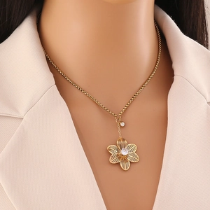 Gros plan d'un collier pendentif fleur dorée avec cristaux clairs sur un cou féminin