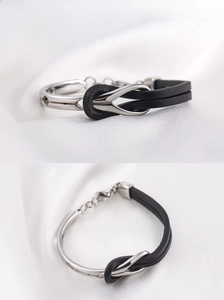 Close-up of titanium steel bracelet with black leather cord and lobster clasp on silk