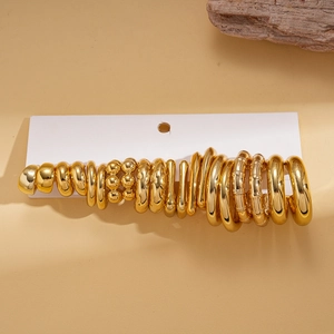 Close-up of a 20-piece gold geometric earring set on a white card display with wood accent