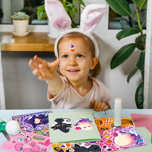 Close-up of a child playing with Halloween cartoon stickers featuring pumpkins and ghosts
