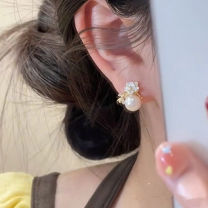 Detailed close-up view of elegant floral pearl earrings worn by a model in classic French style