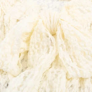 Detail shot of the cream-white lace fabric and delicate bow knot on the romper