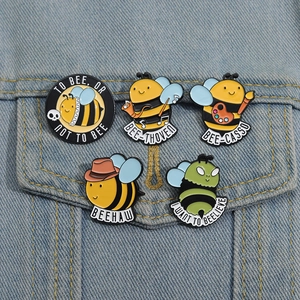 Détail de cinq épinglettes en émail abeille avec jeux de mots sur une veste en jean