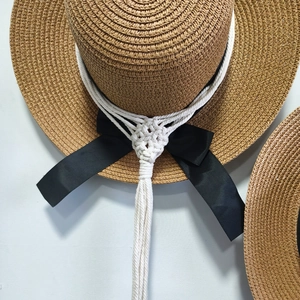 Handwoven macrame hat holder with straw sun hat and black ribbon bow wall decor