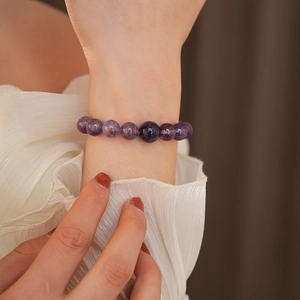 Nahaufnahme eines eleganten Armbands aus tiefvioletten Amethystperlen am Handgelenk