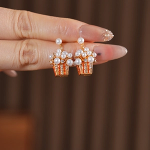 Macro shot of gold-plated popcorn earrings with white pearls and orange cubic zirconia