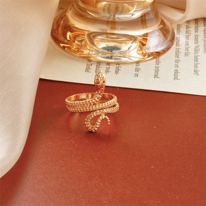 Vintage gold snake wrap ring with scale texture and small rhinestone eyes on dark leather