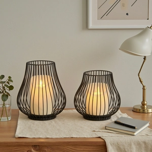 Set of two black iron wire candle holders with LED candles on a wooden table