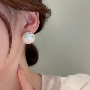 On-ear shot of oversized white pearl earrings featuring elegant glossy round finish
