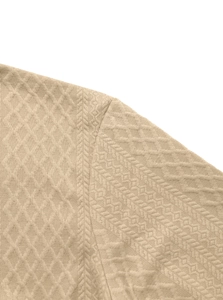 Macro shot of khaki long sleeve shirt fabric with 3D diamond and arrow textured patterns