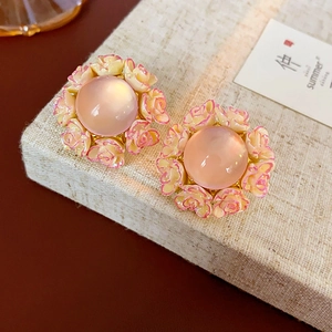Macro detail of French style floral earrings with pink resin stone and rose petals