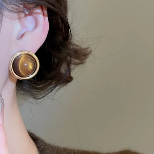 Close-up of 18k gold plated tiger eye stud earrings on ear with brown gemstone