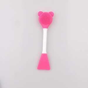 Detailed macro view of a pink dual-sided silicone face brush with bear-shaped bristles