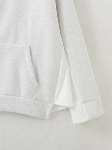 Close-up of light gray hoodie featuring white shirt hem contrast and side slit detail