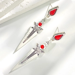 Detailed macro view of Gothic sword earring with red gemstone on stone texture