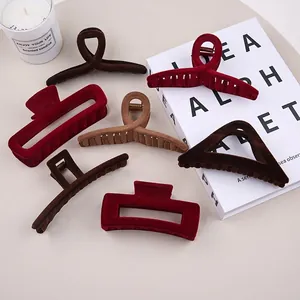 Elegant large flocked hair claw clips in autumn winter colors on a minimalist desk