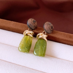 Detail of vintage earrings featuring dark wood circles and green resin pendants