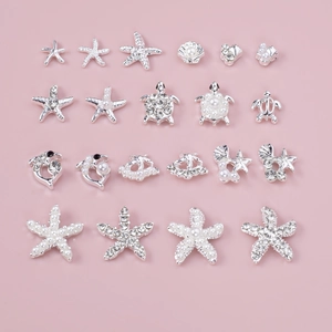 Silver starfish and shell nail charms set with pearls and rhinestones on pink background