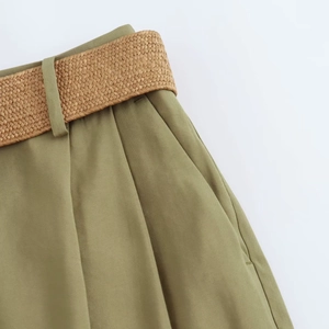 Close-up of olive green casual shorts featuring a woven brown belt and twill texture