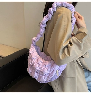 Detailed texture of purple ruched cloud tote bag shown on a khaki trench coat model