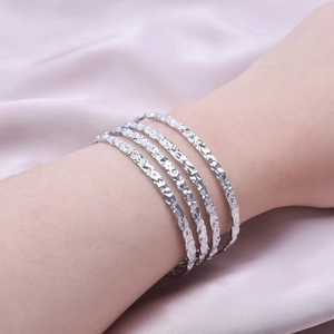 Macro detail of four silver-plated hammered texture cuffs on a model's wrist