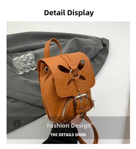 Détail macro du mini sac à dos en cuir orange avec design papillon et boucle en métal
