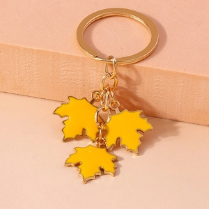 Detailed shot of three yellow maple leaf charms on a golden alloy keychain ring