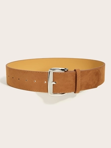 Detail of a brown suede wide belt with a polished silver buckle on a clean cream background
