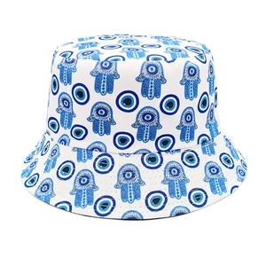 Detail of white canvas bucket hat featuring blue Evil Eye and Hamsa Hand patterns