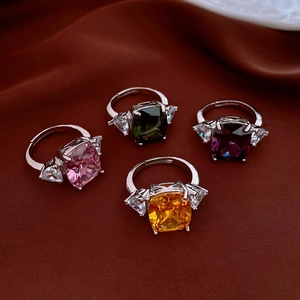 Detail of four colorful rectangular gemstone rings with side zircon on silk background