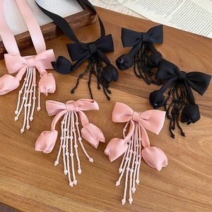 Detailed close-up of ribbon bow earrings with tulip beaded tassels on a vintage background