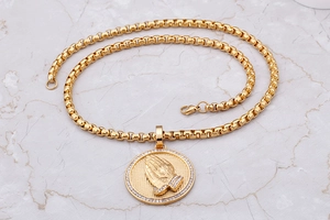 Detailed close-up of 18K gold plated praying hands pendant with crystal accents on a box chain