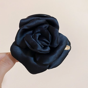 Vista dettagliata della molletta a rosa in raso nero con petali di seta e finitura lucida