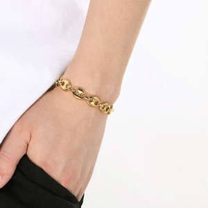 Close-up of golden stainless steel pig nose link chain bracelet worn on a female wrist