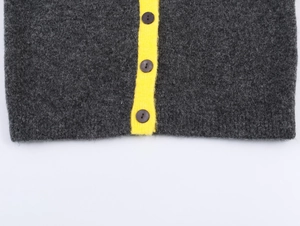 Detail of dark grey knit cardigan featuring contrasting yellow placket and brown buttons