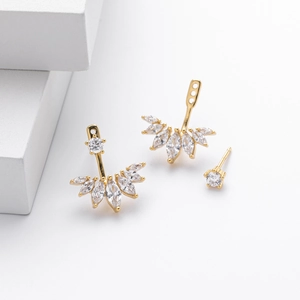 Detail of gold S925 silver earrings with marquise cubic zirconia on a white geometric stand