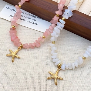 Detailed flat lay of pink and white beaded necklaces featuring golden starfish pendants