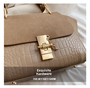 Detail of tan embossed crocodile leather handbag with gold metal lock and chain accessory