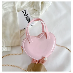 Pink heart-shaped jelly bag with gold chain strap held against a stylish background