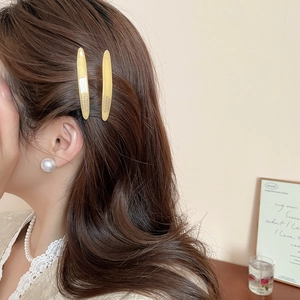Dettaglio di due fermagli per capelli in acrilico giallo su capelli castani, stile retrò