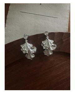 Detail of silver leaf pendant earrings with zircon on a vintage wooden tray background