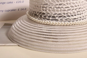 Vue détaillée d'un chapeau de soleil en dentelle blanche avec garniture de perles chic