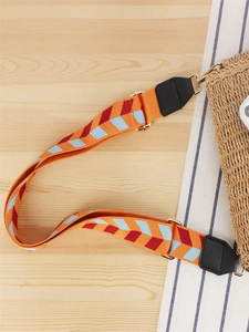 Handmade woven crossbody bag with geometric orange strap on a beach straw tote bag