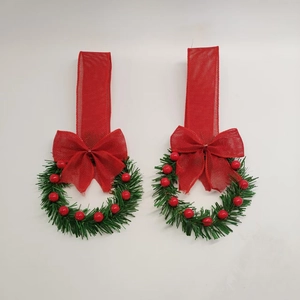 Close-up of two mini Christmas cabinet wreaths with red berries and burlap ribbon bows