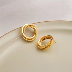 Detailed close-up of triple-layered golden spiral earrings on a ceramic dish