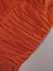 Detail shot of orange pleated tulle fabric layers with soft mesh texture and fine craftsmanship