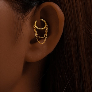 Dettaglio macro di un earcuff a doppia catena dorata sulla cartilagine di un orecchio