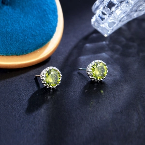 Macro shot of green zircon crown stud earrings with classic silver multi-claw setting
