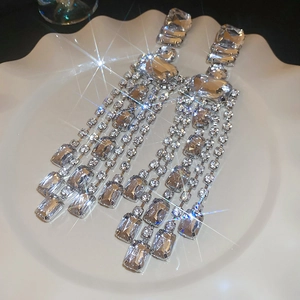 Detail of silver long tassel earrings with sparkling rhinestones in a white ceramic dish